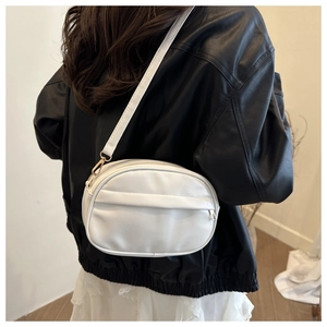 Detail of white PU leather crossbody bag featuring hidden zipper pocket and gold hardware