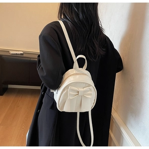 Detailed back view of a creamy white mini bow backpack with slim straps on model