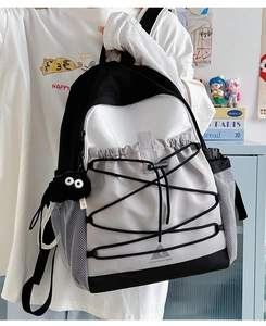 Close-up of contrast color backpack with elastic drawstrings and plush coal sprite charm