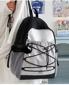 Detail of multi-color canvas backpack featuring elastic cords and side mesh pocket