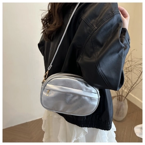 Detail of silver metallic crossbody shell bag with adjustable strap on a model