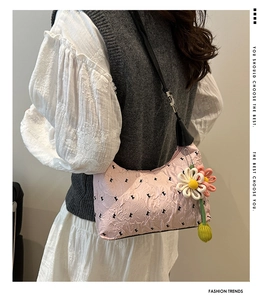 Detail of pink pleated nylon shoulder bag with 3D floral charm and letter pattern