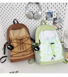 Detail view of canvas backpack featuring drawstring pocket, mesh side pocket and plush charm