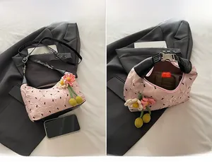 Detail of pink pleated hobo bag with knit flower charm and adjustable shoulder strap