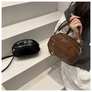 Detail of vintage style crossbody bags in black and brown shiny faux leather