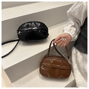 Close-up of sleek black and brown crossbody bags with glossy finish on concrete steps