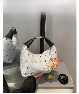 Detail of white pleated handbag with bird prints, leather handle and floral pendant