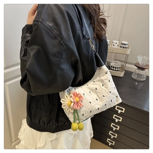 Detail of white embossed shoulder bag with K letter print and floral charm accessory