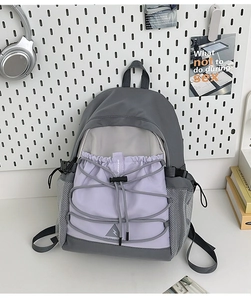 Detail of grey and purple canvas backpack with front drawstring and mesh side pocket