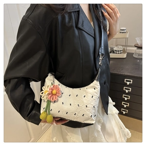 Dettaglio borsa a mezzaluna bianca con stampa K e ciondolo decorativo a fiore in maglia