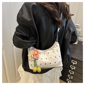 Détail du sac blanc brodé de lettres K avec un pendentif fleur en tricot fait main