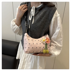 Detailed texture of pink pleated hobo bag with black bow prints and floral charm