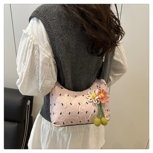 Détail de la texture du sac plissé rose avec breloques artisanales fleurs et cerises