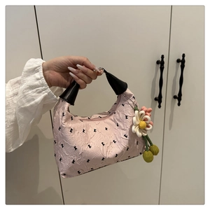 Détail du sac à main plissé rose avec pendentif tournesol et poignées noires