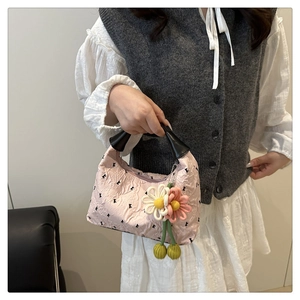 Détail du sac à main en jacquard rose avec nœuds noirs et breloque fleurie tissée 3D