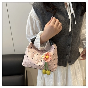 Dettaglio della borsa rosa con texture, motivi a fiocco nero e ciondolo floreale