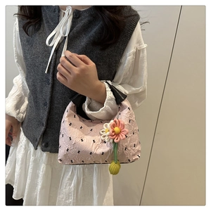 Détail du sac à main plissé rose avec nœuds noirs et breloque fleur au crochet