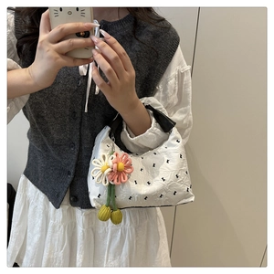 Détail du sac à main plissé blanc avec nœuds noirs et accessoire de fleur tissée