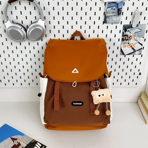 Detail of orange and brown color-block backpack with nylon texture and cute doll charm