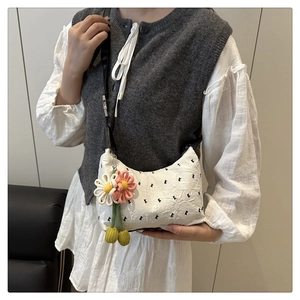 Détail d'un sac matelassé blanc avec breloques marguerites et bandoulière en cuir noir