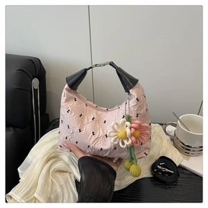 Détail du sac à main plissé rose avec imprimés floraux et breloques de fleurs