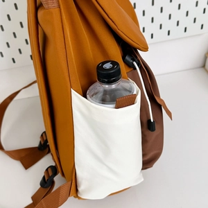 Close-up of the side pocket on a color-block backpack holding a water bottle securely