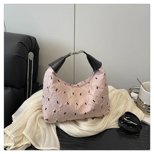 Détail du sac à main jacquard rose avec motifs de nœuds noirs et poignées en cuir