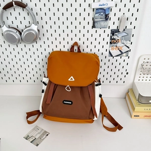 Detail of color-block hiking backpack featuring orange and brown nylon on a white desk