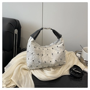 Détail du sac à main blanc plissé avec motifs de cœur et bandoulière noire amovible