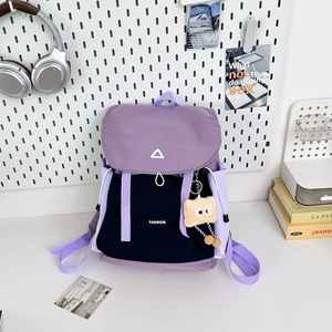 Detail of purple and black nylon backpack with fashion text and plush keychain