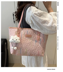 Detail of pink embroidered canvas tote with wave patterns and white cloud charm