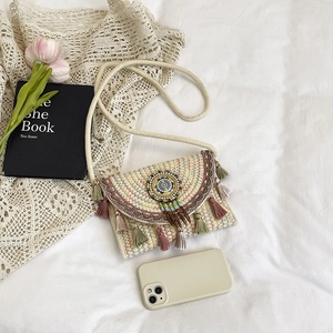 Bohemian woven envelope bag with colorful tassels and ethnic bead embroidery on a white fabric
