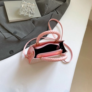 Detail of pink crossbody bag with woven handle showing interior zipper compartments