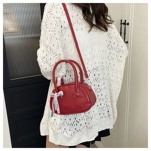 Detalle del bolso bowling rojo con lazo rosa decorativo y correa ajustable