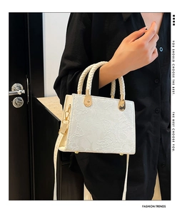 Detailed view of white crossbody bag with floral texture and braided handle