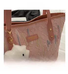 Dettaglio borsa tote rosa in tela con ricami colorati, hardware dorato e charm nuvola
