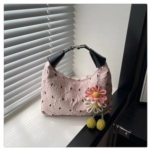 Détail du sac Hobo rose avec motif K embossé et une breloque florale en peluche