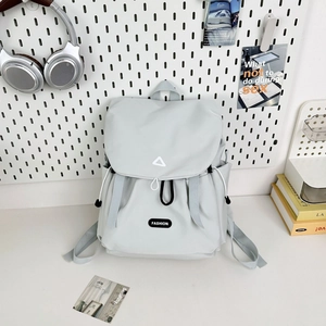 Detail of light gray water-resistant backpack with drawstring closure and logo on desk