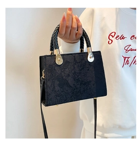 Detail of black jacquard fabric texture and gold bead fasteners on the handbag
