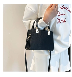Detail of black jacquard shoulder bag featuring woven handles and silver teardrop accents