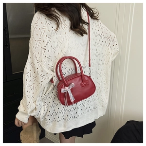 Primer plano del bolso Boston de cuero rojo con lazo a cuadros rosa y asas dobles cortas