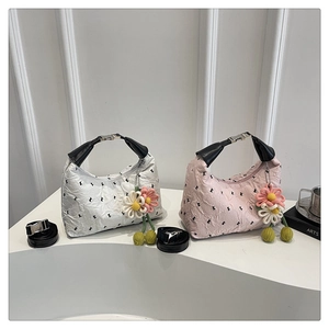 Détail de sacs à main froncés blanc et rose avec des charmes de fleurs tricotées