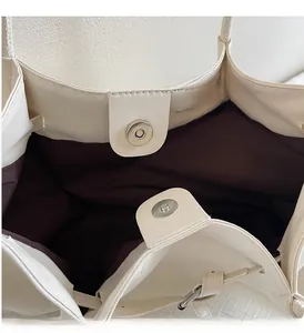 Détail du sac à main tressé blanc cassé montrant le fermoir magnétique et la doublure foncée