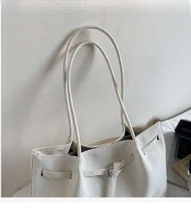 Détail d'un cabas blanc cassé montrant la texture tressée, les anses fines et la boucle