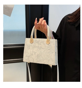 Close-up of white lace floral handbag with woven handles and gold metal connectors