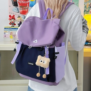 Detailed back view of a purple and navy color-block backpack with a brown plush charm