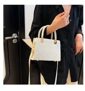 Detail view of white PU bag featuring 3D floral embossing and woven leather handle