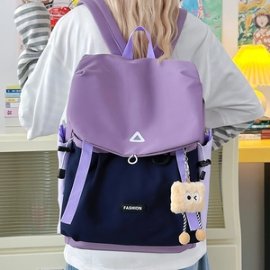 Detail of color-block nylon backpack with adjustable straps and plush eye pendant