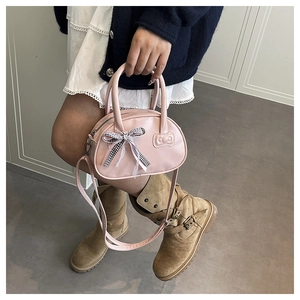 Detalle del bolso rosa con lazo, diseño en relieve y correa ajustable para el hombro
