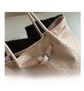 Detail view of pink woven leather tote with adjustable strap and plush bear charm